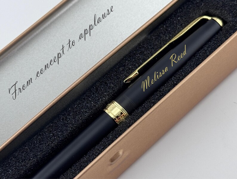 May include: A black pen with gold accents and the name "Melissa Reed" engraved in gold lettering. The pen is presented in a gold-colored box with the phrase "From concept to applause" printed inside.