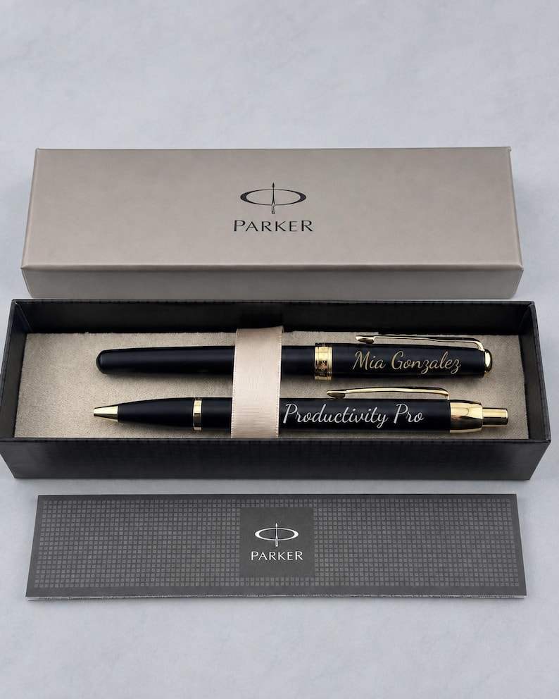 May include: A black Parker pen set with gold-tone accents inside a rectangular gift box. The top pen is engraved with the name Mia Gonzalez, and the bottom pen is engraved with the text Productivity Pro. The box lid features the Parker logo.