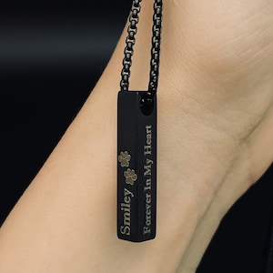 May include: Black chain necklace with a black rectangular pendant engraved with "Smiley Forever In My Heart" and paw prints.