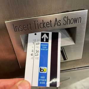 May include: A blue and black ticket with white text that reads "Insert this side up" and "See other side". The ticket has a black bar code and a yellow logo with the letter "b" and the word "lemonade".