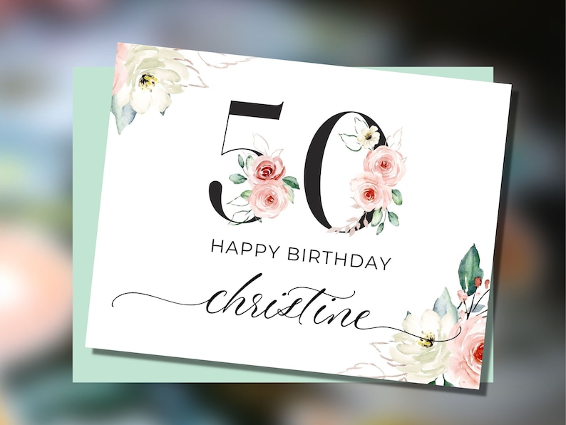 May include: A white card with a black number 50 decorated with pink and white flowers. The text "Happy Birthday Christine" is written below the number.
