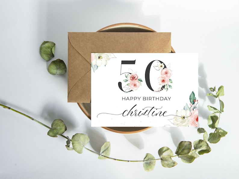 May include: A white card with a floral design featuring the number 50 in black with pink flowers. The text "Happy Birthday Christine" is written in black cursive.
