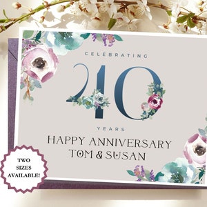 May include: A light gray card with a floral design and the text "Celebrating 40 Years Happy Anniversary Tom & Susan". The card is decorated with watercolor flowers in shades of pink, blue, and green. The number 40 is in a dark blue color.