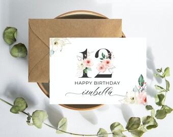 May include: A white card with a floral design and the number 12 in black. The text "Happy Birthday Isabella" is written in black cursive.