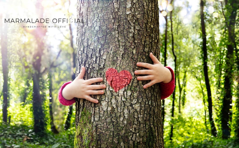 May include: A child's hands reach around a tree trunk, embracing it. A red heart is painted on the bark of the tree. The text "MARMALADE OFFICIAL HANDCRAFTED WITH LOVE" is at the top of the image.