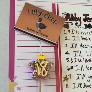 May include: A birthday-themed image featuring a star-shaped decoration with the number 18, a small crown, and a Lucky Duck Chinese restaurant takeout box. The background includes a pink and white wishlist.