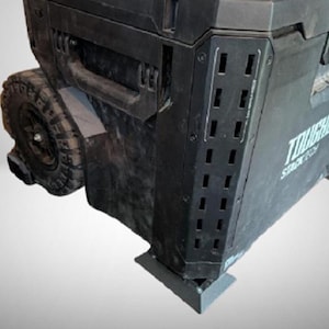 May include: Black rolling toolbox with the text "TOUGHBUILT" and "STACK TECH". The toolbox has a handle, a wheel, and rectangular vents. Designed for tool storage, it features a robust build.