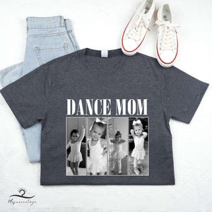 May include: A dark gray t-shirt with the text "DANCE MOM" printed in white. The shirt features three black and white photos of young girls in dance attire.