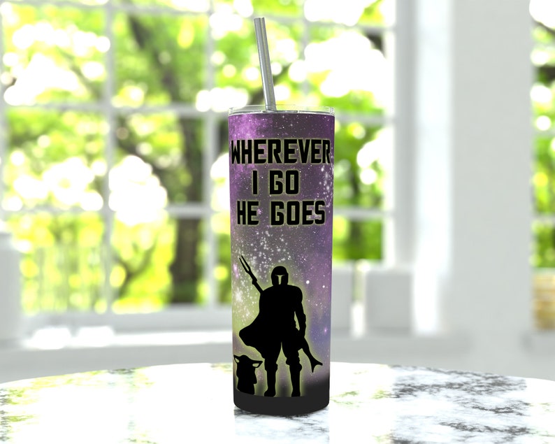 Puede incluir: Un vaso de acero inoxidable con un estampado de galaxia p&uacute;rpura y negro. El vaso presenta una silueta de un Mandaloriano y Grogu con el texto "Wherever I go he goes".