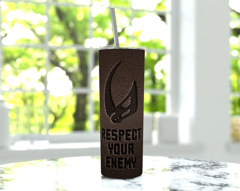 Puede incluir: Un vaso de acero inoxidable marr&oacute;n con una textura de cuero negro y un s&iacute;mbolo mandaloriano. El vaso tiene el texto "Respect Your Enemy" impreso en &eacute;l.