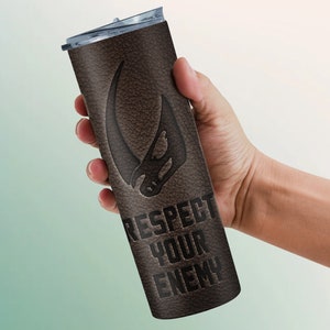 Puede incluir: Un vaso de acero inoxidable con textura de cuero marr&oacute;n con un s&iacute;mbolo mandaloriano negro y el texto "Respect Your Enemy".