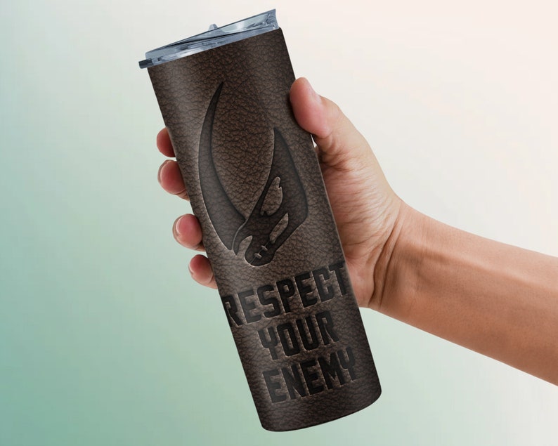 Puede incluir: Un vaso de acero inoxidable con textura de cuero marr&oacute;n con un s&iacute;mbolo mandaloriano negro y el texto "Respect Your Enemy".