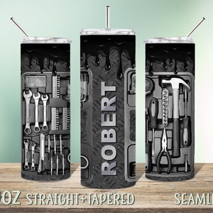 May include: A black and gray 20 oz. stainless steel tumbler with a design of tools in a toolbox. The tumbler is straight and tapered and has a seamless finish. The name "ROBERT" is printed on the side of the tumbler.