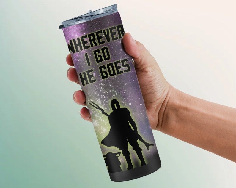 Puede incluir: Un vaso de acero inoxidable negro con un estampado de galaxia y el texto "WHEREVER I GO HE GOES". Una silueta de un Mandaloriano y Grogu se encuentra en el centro del vaso.