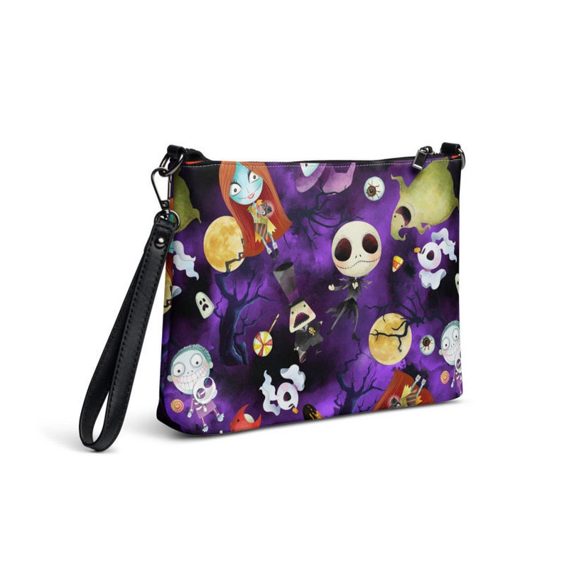 May include: A purple and black crossbody bag with a repeating pattern of characters from The Nightmare Before Christmas. The characters include Jack Skellington, Sally, and Zero. The bag has a black strap.