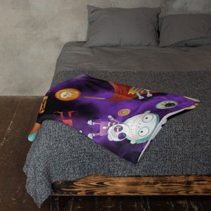 May include: Purple and black Halloween themed throw blanket with a cartoon skeleton and a smiling monster with candy and a witch's hat in the background.