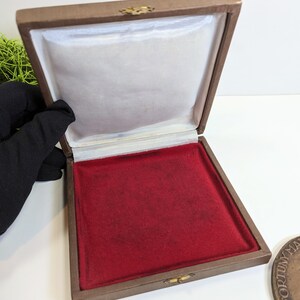 May include: A brown velvet-lined box with a red velvet interior. The box is open and empty.
