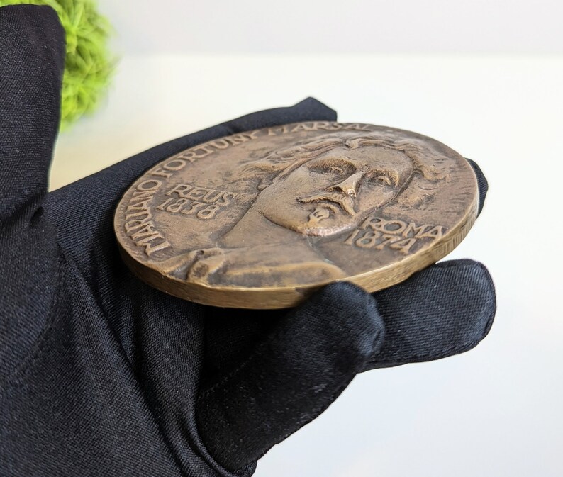 May include: A bronze medal with a portrait of a man on one side and the text "D.D. FORTUNY. REUS 1838 ROMA 1874" on the other side.