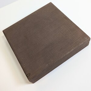 May include: A brown cardboard box with a textured surface. The box is closed and has a hinged lid.