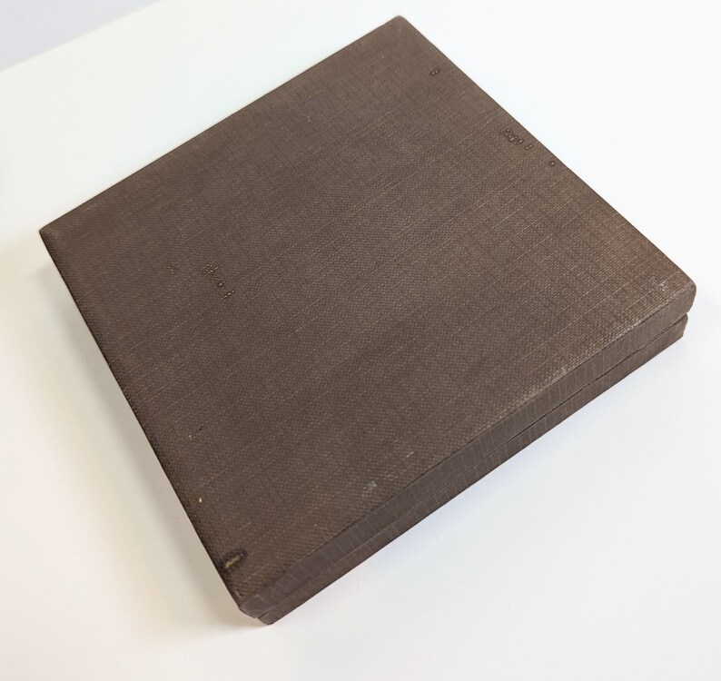 May include: A brown cardboard box with a textured surface. The box is closed and has a hinged lid.