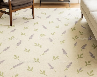 May include: Cream-colored area rug with a repeating pattern of lavender sprigs and green leaves. The rug is placed in a living room setting, with a chair, sofa, and shelving unit visible in the background.