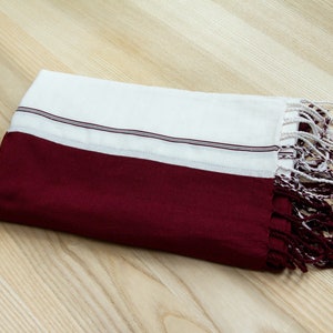 Peut inclure: Une écharpe en coton rayée blanche et bordeaux avec des franges aux extrémités.