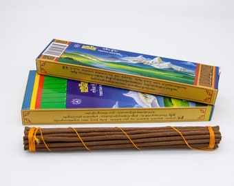 May include: Two boxes of Tibetan incense with a bundle of brown incense sticks tied with orange string. The boxes are gold with blue, green, and red accents. The text on the boxes is in Tibetan.