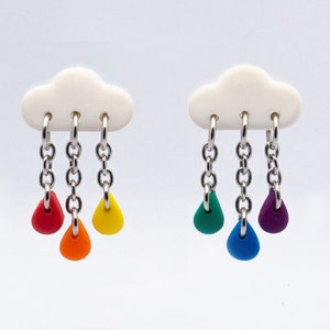 May include: A pair of earrings featuring a white cloud charm with three dangling raindrops. The raindrops are red, orange, yellow, green, blue, and purple.