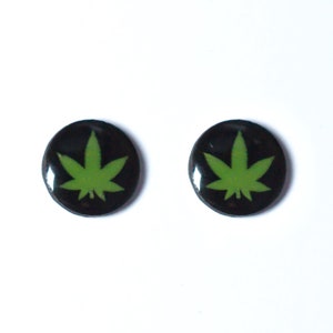 May include: A pair of black stud earrings with a green marijuana leaf design.