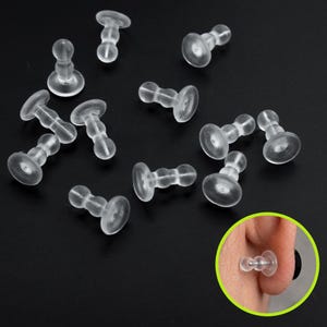 Peut inclure: Plusieurs dos de boucles d'oreilles en plastique transparent sont disposés sur une surface sombre. Chaque dos est composé d'un petit disque rond et d'une tige pour fixer les boucles d'oreilles. Un gros plan montre un dos de boucle d'oreille en cours d'utilisation.