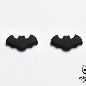 May include: A pair of black bat-shaped stud earrings.
