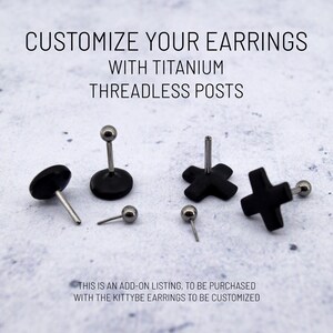 May include: An assortment of black earrings with titanium threadless posts. The image includes various shapes, such as a disc, a ball, and cross shapes. Text on the image reads, "CUSTOMIZE YOUR EARRINGS WITH TITANIUM THREADLESS POSTS."