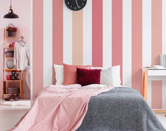 May include: A bedroom with a pink and white striped wall, a bed with a pink and gray blanket, and a black clock on the wall.