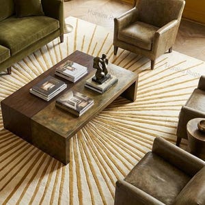 May include: An overhead shot of a living room with a large, rectangular coffee table made of wood and metal. The table is adorned with books and a sculpture. The room features a patterned rug, a green sofa, and leather armchairs.