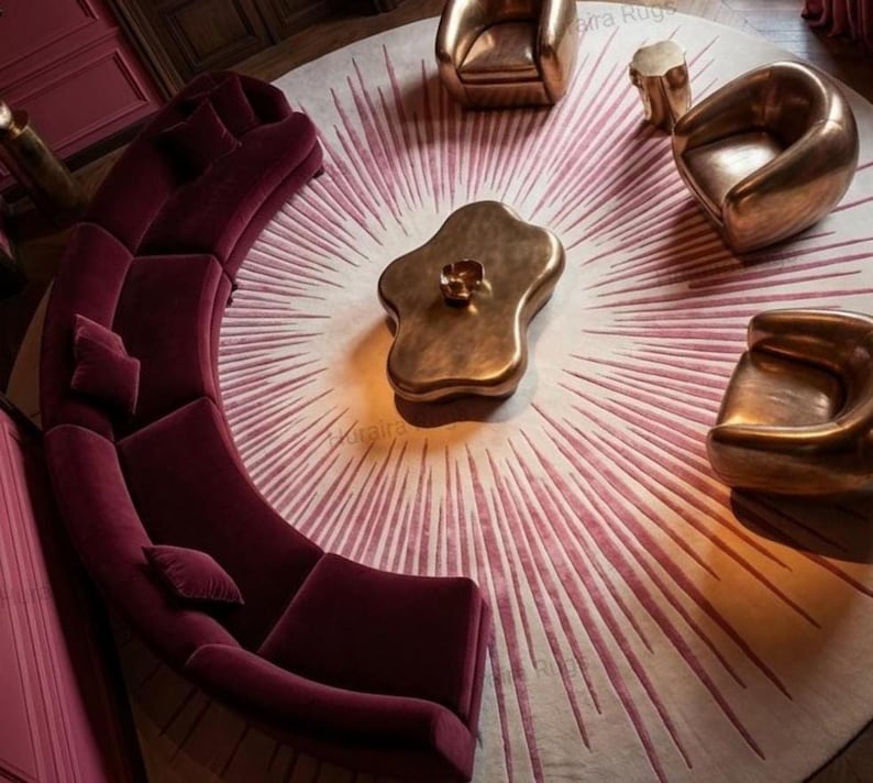 Curved magenta sofa surrounds 8x8 round sunburst rug, warm pink to burgundy rays, modern statement
