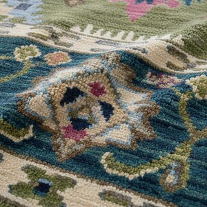 May include: Close-up of a detailed area rug with a floral pattern. The rug features a teal, green, and beige color palette with accents of pink and blue. The texture appears soft and plush.