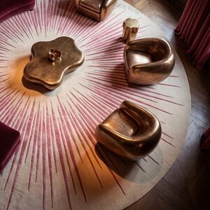 Living room vignette with 8x8 round sunburst rug, pink and beige tones radiating under brass tables