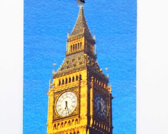 May include: A blue and yellow car air freshener with a picture of Big Ben, a famous clock tower in London, England.