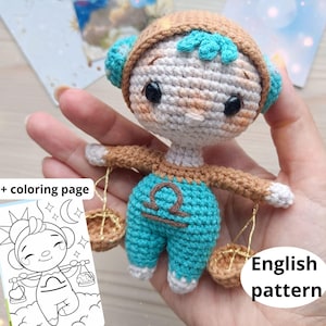 May include: A crocheted Libra zodiac doll with a brown hat and arms, turquoise trousers, and a beige body. The doll holds two small baskets. The image also includes a colouring page and the text "English pattern".