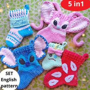 May include: A collection of five handmade crochet Christmas stockings in different colours and designs. The stockings feature a blue and white striped stocking with "MERRY CHRISTMAS" text, a pink character with long ears, a blue character with large ears, a green character with a bow, and a red stocking with white accents. The text "SET English pattern" is also visible.