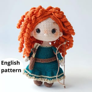 Pode incluir: Boneca de crochê feita à mão com cabelo encaracolado laranja brilhante, vestindo um vestido verde-azulado com cinto marrom e aljava. A boneca tem arco e flecha e é feita com fio bege. O texto "English pattern" é visível.