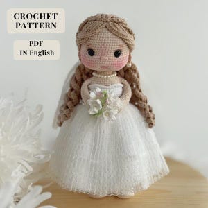May include: A handmade crochet doll dressed as a bride, holding a bouquet of white flowers. The doll has a white dress, a veil, and long brown hair. The text "CROCHET PATTERN PDF IN English" is in the upper left corner.
