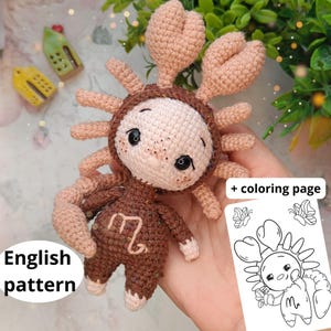 May include: A handmade crochet doll in the shape of a crab, featuring a light brown body, beige claws, and a white face. The doll has black eyes and a brown crab shell. Includes a coloring page. The text "English pattern" is visible.