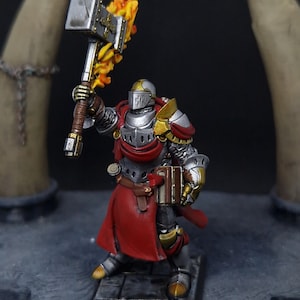 May include: A miniature figure of a knight in silver armor holding a flaming hammer and a book. The knight is wearing a red cape and has a gold helmet.