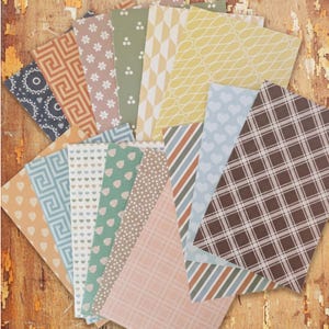 May include: A collection of patterned paper sheets in various designs and colors, including geometric, floral, and striped patterns. The color palette includes shades of blue, green, pink, and brown, arranged in a fan shape.