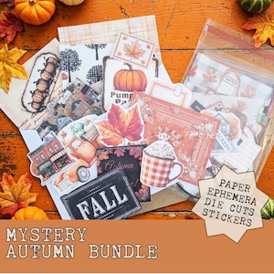 May include: A collection of autumn-themed paper ephemera, die cuts, and stickers featuring illustrations of pumpkins, maple leaves, a mug with whipped cream, a truck, and buildings. A star-shaped label displays the text PAPER EPHEMERA DIE CUTS STICKERS.