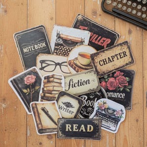 May include: A collection of vintage-style stickers with literary themes. The stickers feature images of books, typewriters, roses, eyeglasses, and text such as "Note Book," "Fiction," and "Read." The color palette includes black, cream, and brown tones.