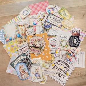 May include: A collection of Easter-themed paper ephemera, including cards, tags, and labels. The designs feature bunnies, eggs, flowers, and text like "Easter Joy" and "Little Chick Spring Market." The color palette includes pastels and vintage-inspired graphics.