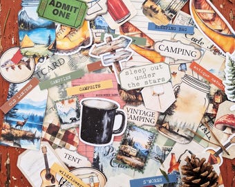 May include: A collection of camping-themed paper ephemera, including a black mug, a canoe, and a compass. Text includes "ADMIT ONE", "CAMPING", "sleep out under the stars", and "S'MORES". The color palette is warm, with shades of brown, orange, and green.