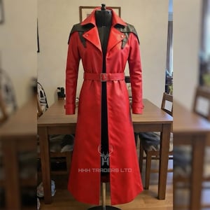 May include: A long, red leather trench coat with black shoulder accents and a matching belt. The coat is displayed on a mannequin, showcasing its tailored fit and design. The coat has a classic trench coat style with a collar and button details.